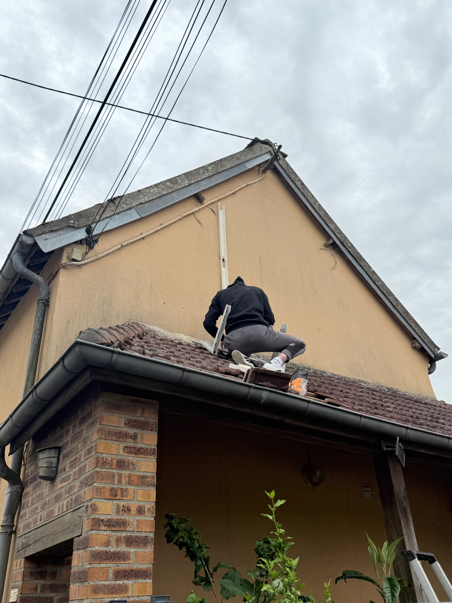 Pose des liaisons frigorifiques en façade par un technicien sur le toit